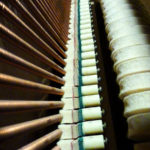 Photo looking down along the strings of an upright piano.